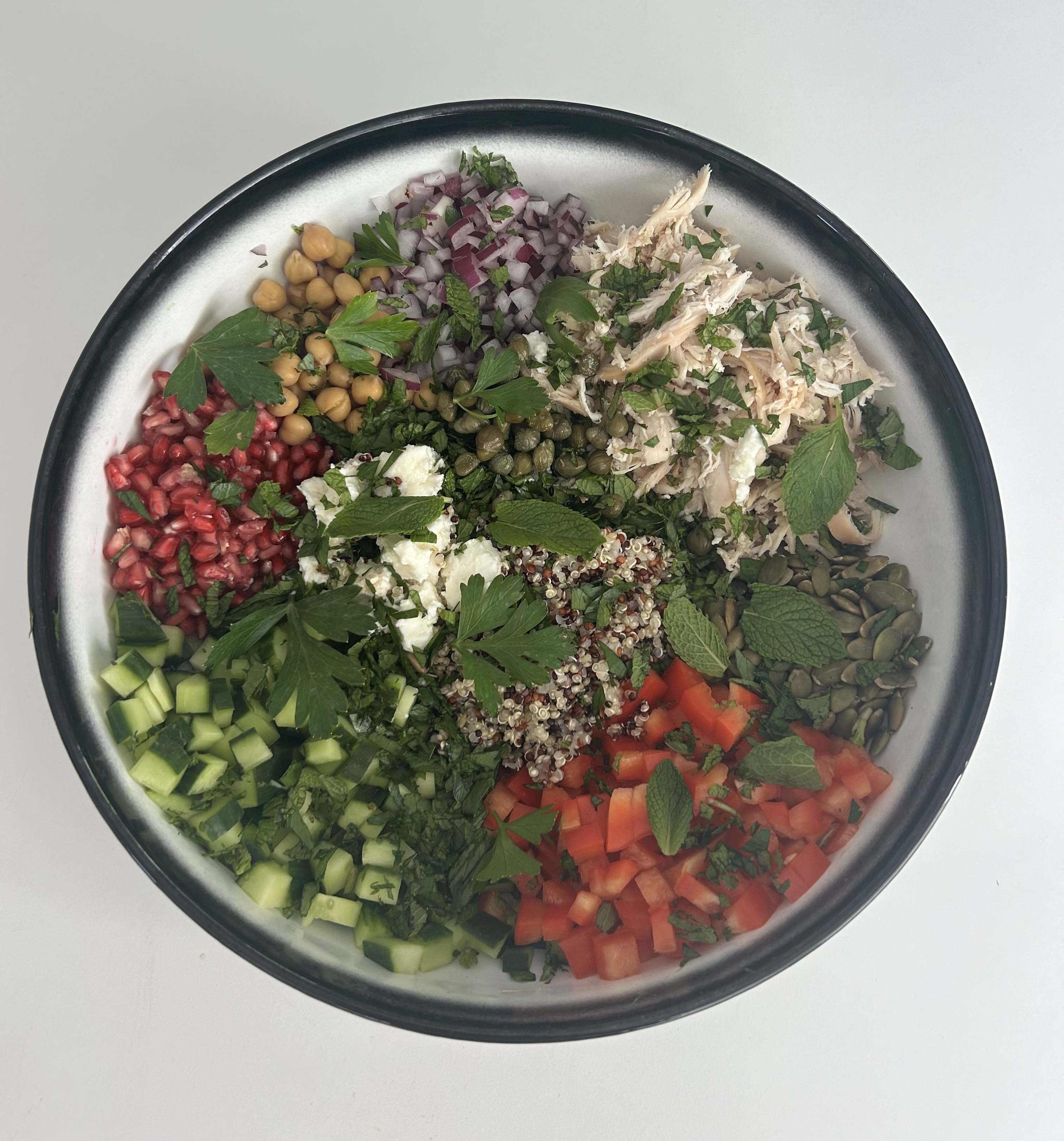 Chicken quinoa crunch salad with cucumber, tomato, pomegranate, feta and herbs
